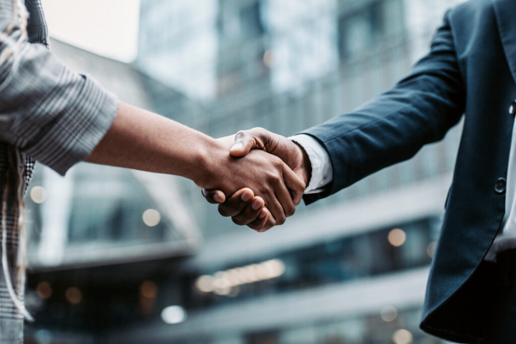 Close-up of two people shaking hands in a professional setting, symbolizing a successful business connection.